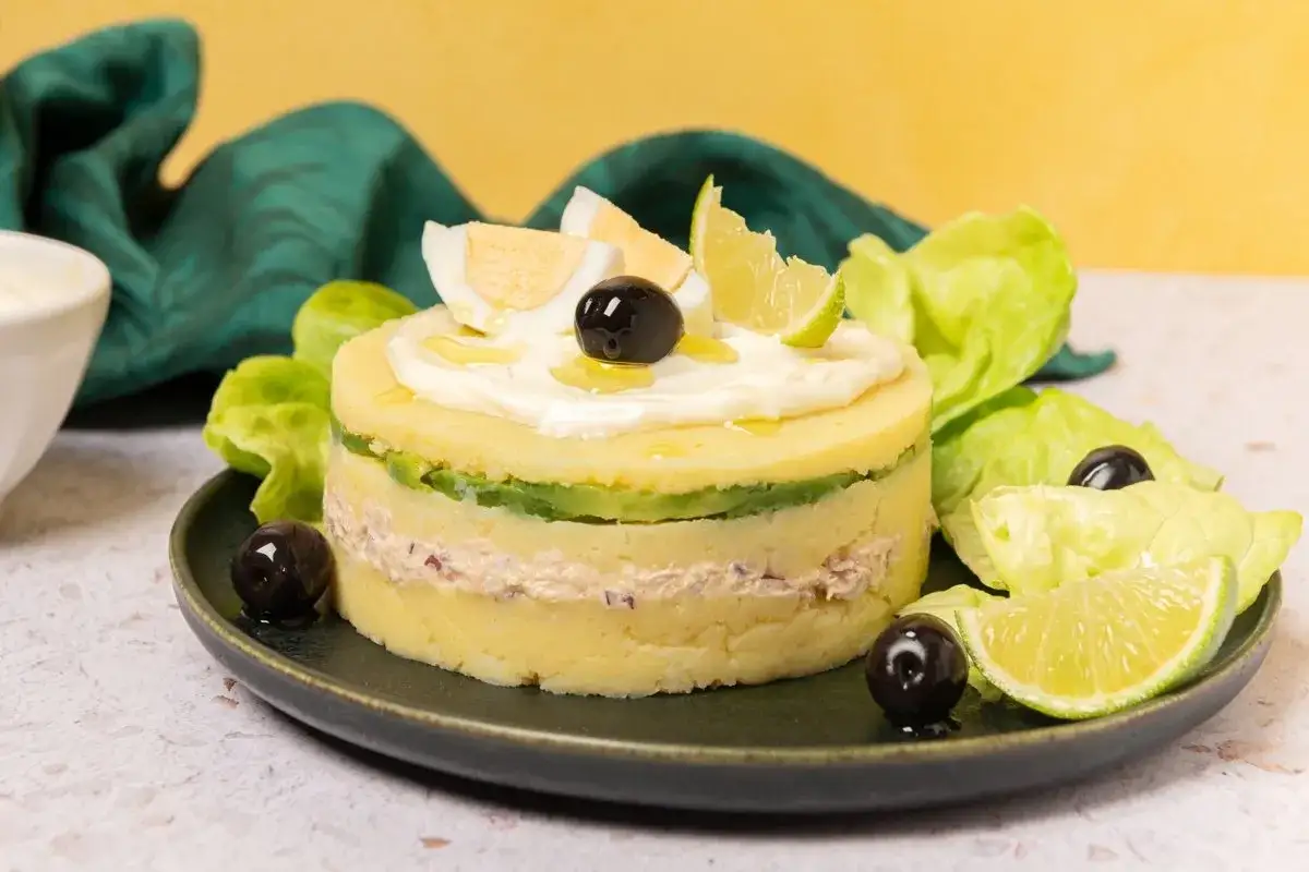 Deliciosa causa lime&ntilde;a en capas, adornada con huevo duro, aceitunas y rodajas de lim&oacute;n.