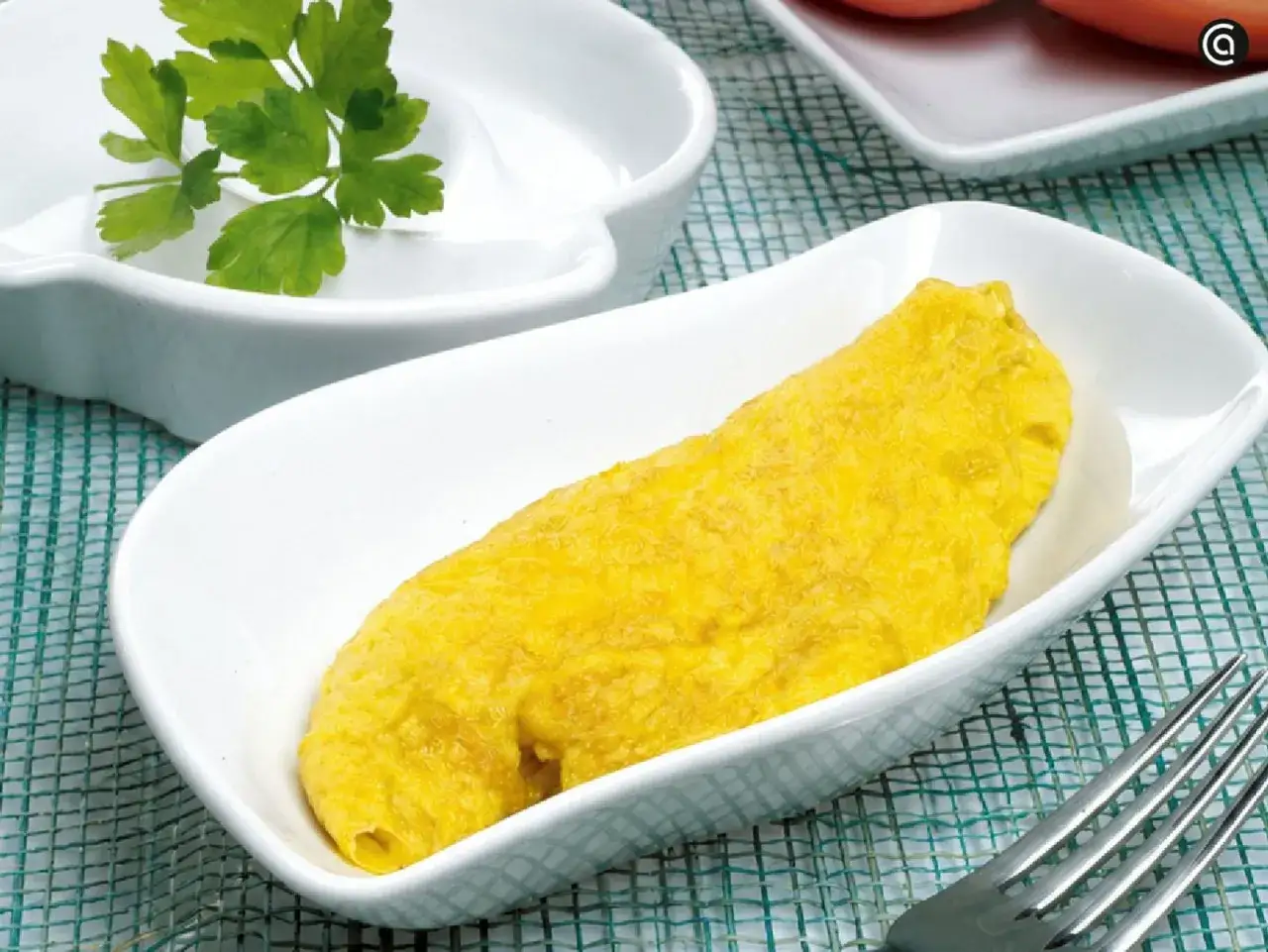 Tortilla francesa dorada y esponjosa en un plato blanco, lista para disfrutar.