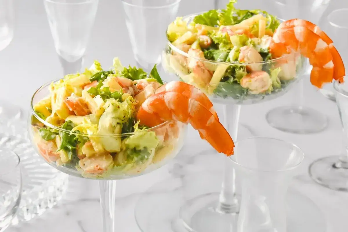 Delicioso coctel de gambas servido en copas elegantes, adornado con gambas enteras.