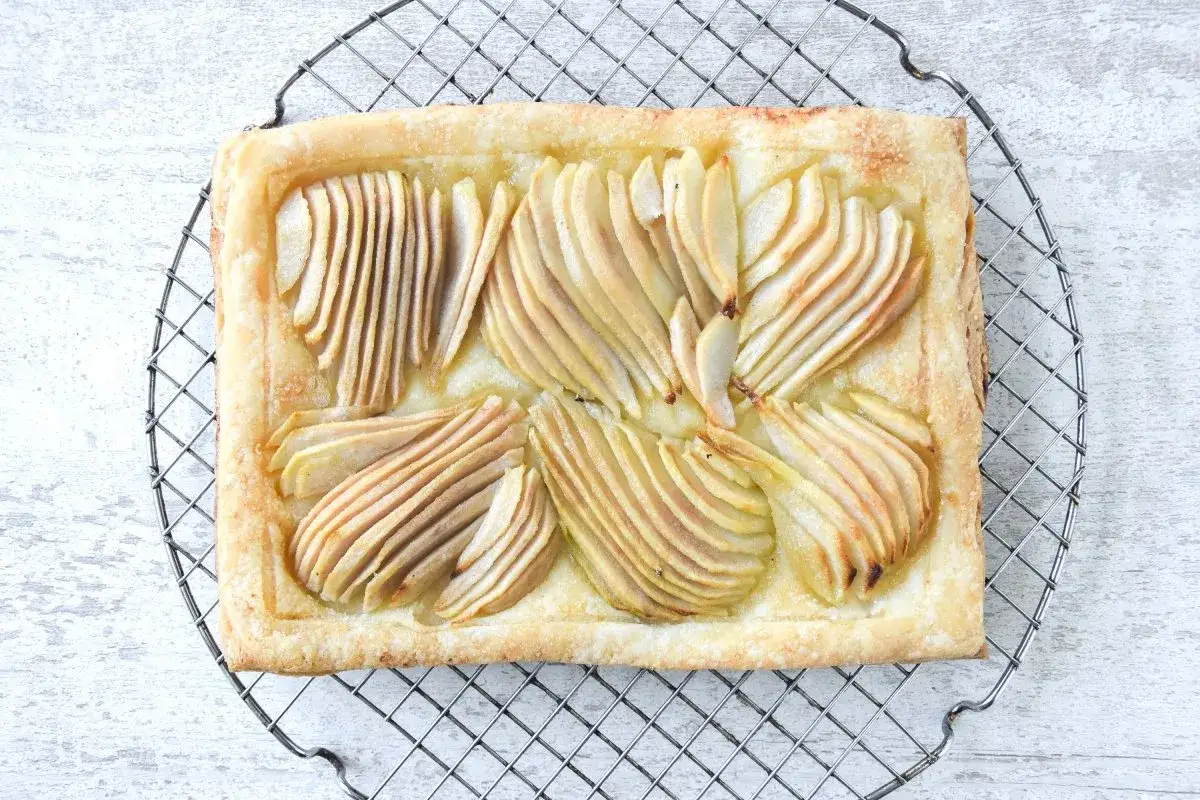Deliciosa tarta de pera y hojaldre, con peras finamente cortadas y doradas sobre una base crujiente.