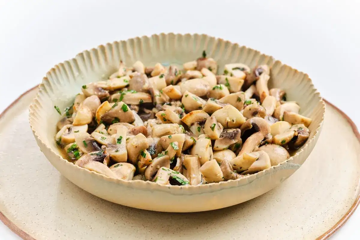 Un bol de champiñones salteados con perejil picado, ideal para tus recetas con champiñones.