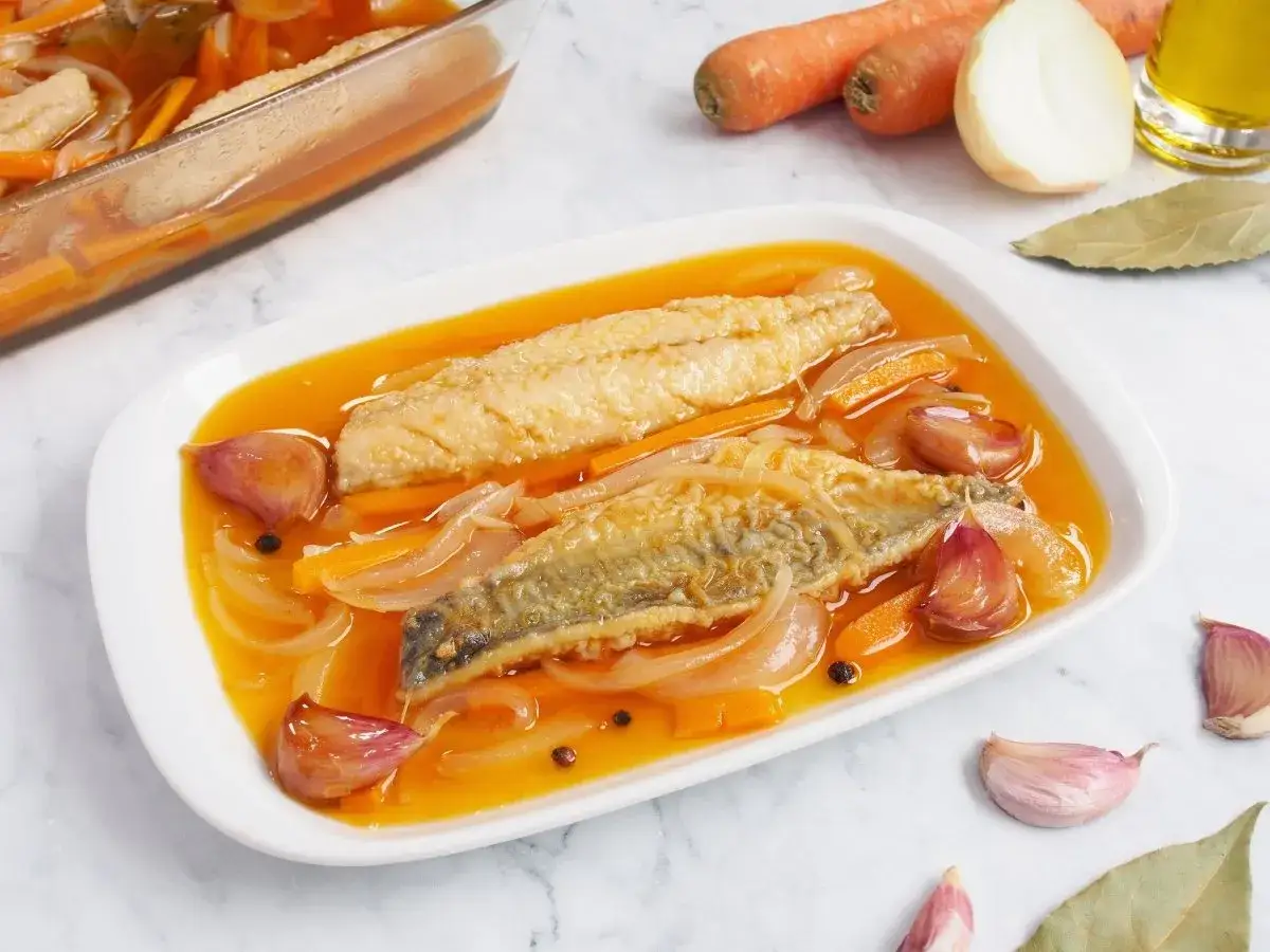 Dos filetes de caballa en escabeche, nadando en un l&iacute;quido dorado con cebolla, zanahoria y ajos.