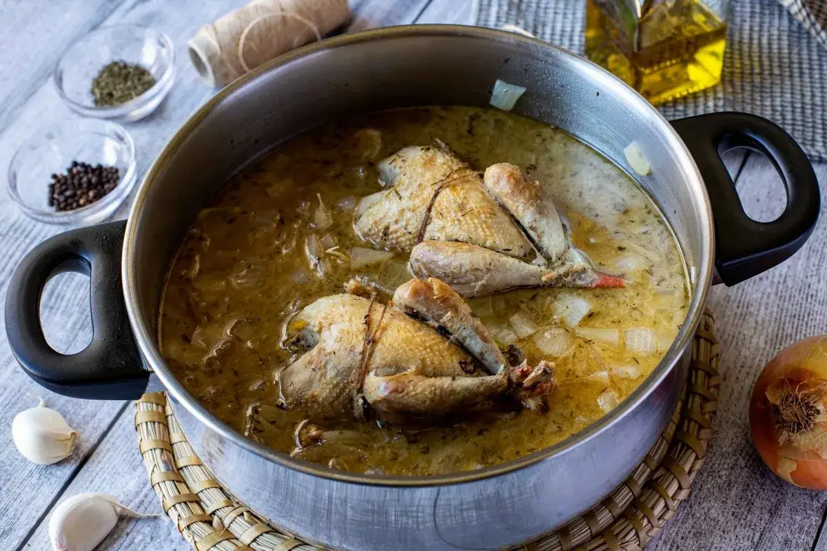 Perdices a la toledana cocinándose en una olla con cebolla y especias.