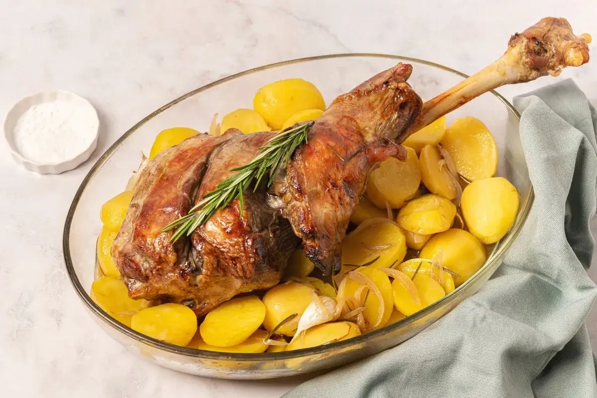 Pierna de cordero al horno dorada y jugosa, servida con patatas asadas, romero y ajo. Un festín listo para disfrutar.