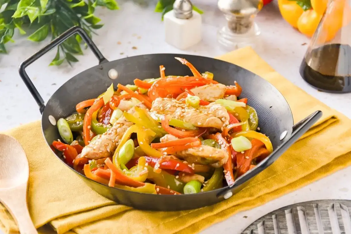 Wok de pollo con pimientos de colores, zanahoria y cebolleta, espolvoreado con semillas de s&eacute;samo.