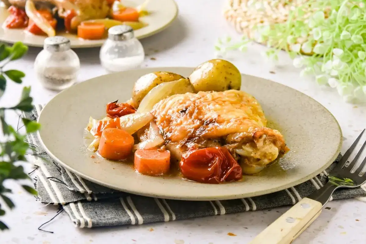 Contramuslos de pollo asados con patatas, zanahorias y tomates. Un plato casero y delicioso.