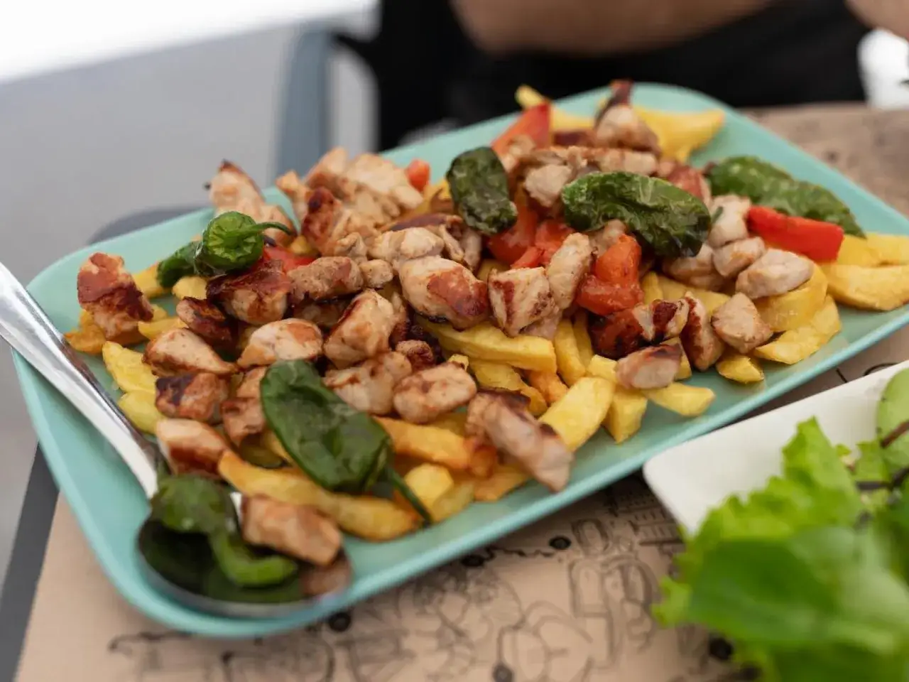 Raxo con patatas, pimientos verdes y trozos de tomate. Un plato generoso y apetitoso.