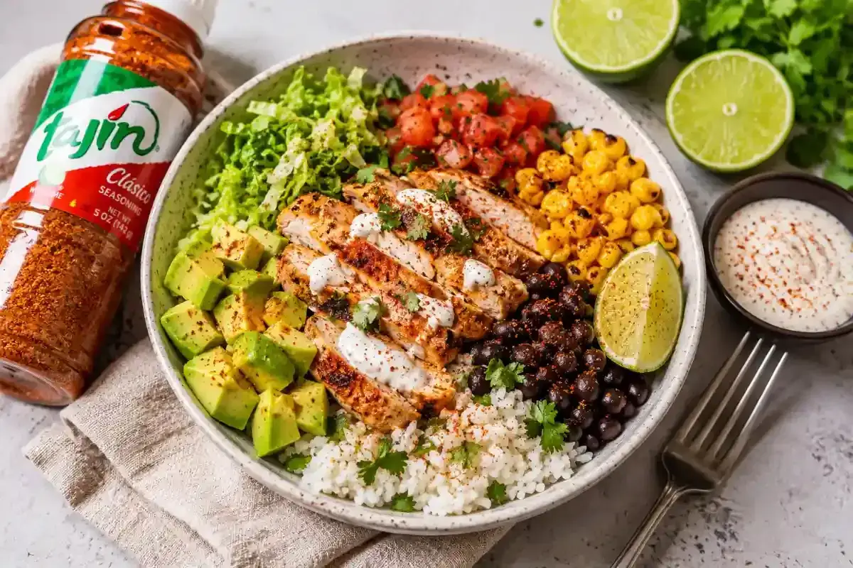 Bowl de pollo con aguacate, frijoles negros, ma&iacute;z, tomate y arroz, sazonado con taj&iacute;n.