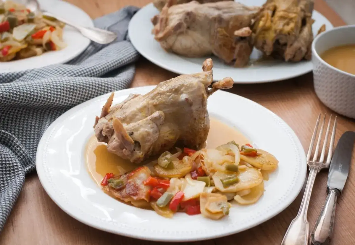 Un plato de pollo a la toledana con patatas y pimientos.