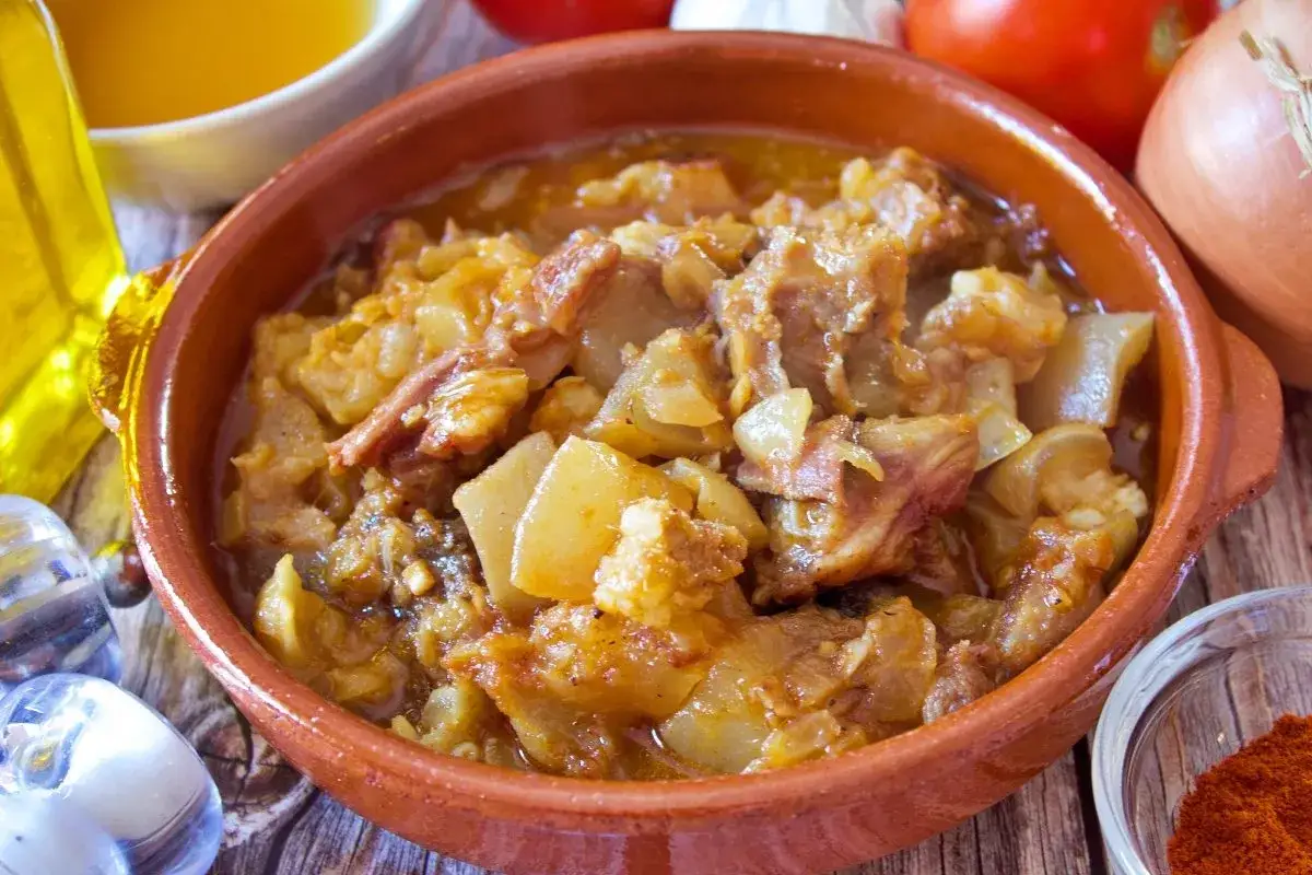 Un reconfortante plato de cap i pota, cocido a fuego lento con patatas y especias, servido en una cazuela de barro.