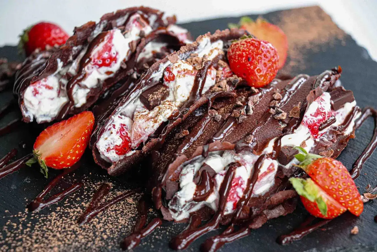 Deliciosos crepes de chocolate rellenos de crema y fresas, ba&ntilde;ados en sirope de chocolate. Una receta irresistible.