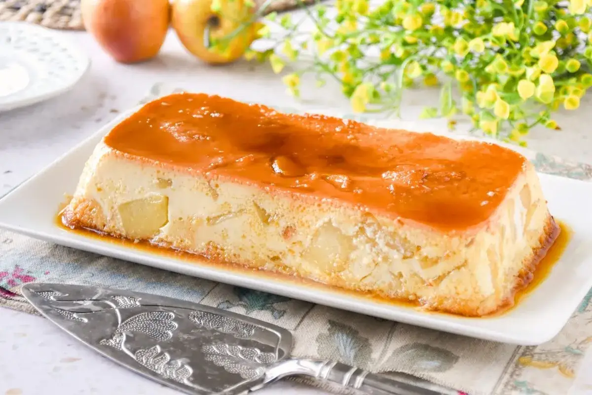 Pudin de manzana cremoso con caramelo líquido, trozos de manzana visibles.