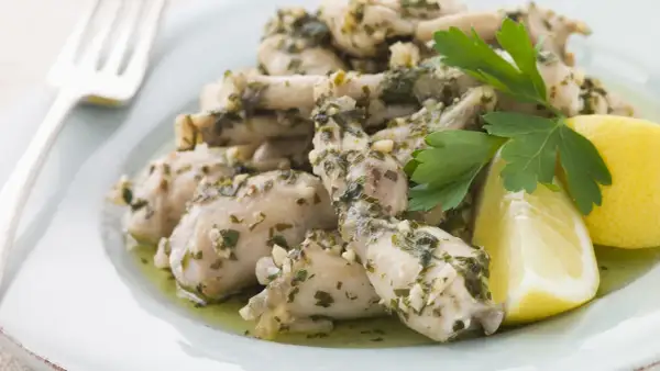 Deliciosas ancas de rana en salsa de ajo y perejil, servidas con gajos de limón. Una receta clásica para disfrutar.
