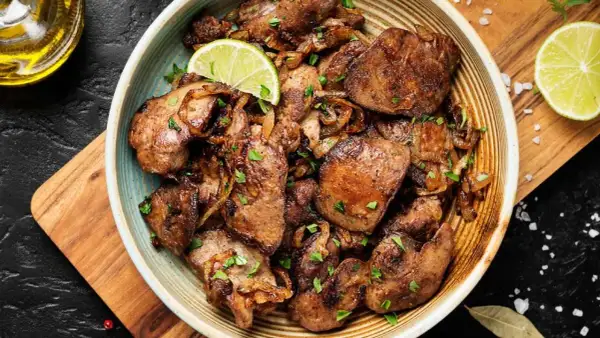 Sabrosos higaditos de pollo encebollados, salpicados de perejil fresco y adornados con rodajas de lima. Un plato casero irresistible.
