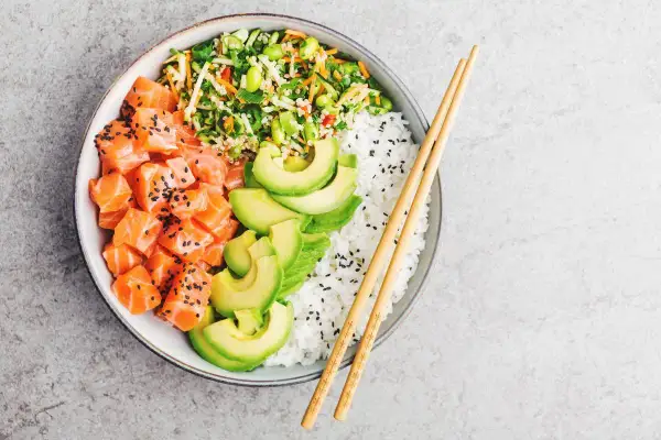 Un delicioso poke de salmón con aguacate, arroz blanco y vegetales frescos.