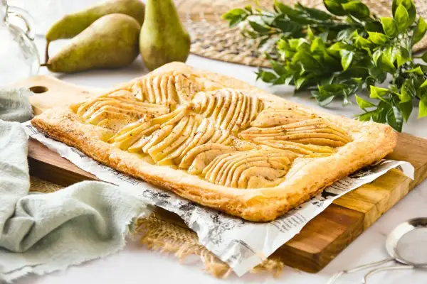 Deliciosa tarta de pera y hojaldre, con finas láminas de pera dispuestas sobre una base dorada y crujiente.