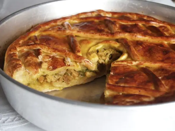 Empanada de carne dorada y crujiente, con un relleno jugoso visible en un corte. Perfecta para compartir.