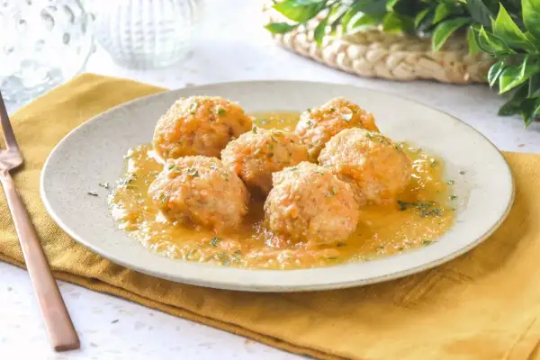 Sabrosas albóndigas de pollo en salsa, servidas en un plato con perejil picado. Un plato casero y reconfortante.