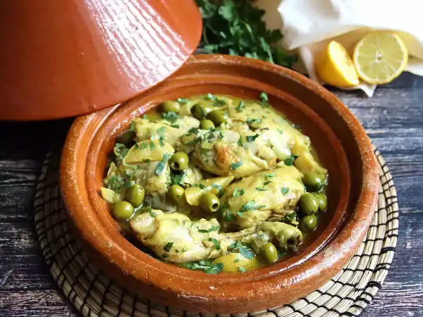Tajín de pollo con aceitunas verdes y limón, servido en una cazuela de barro tradicional.