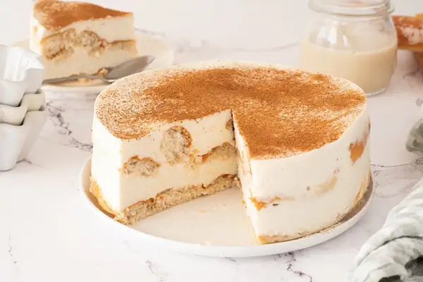 Tarta de horchata y fartons, con bizcocho y crema, espolvoreada con canela. Una porción ya servida.