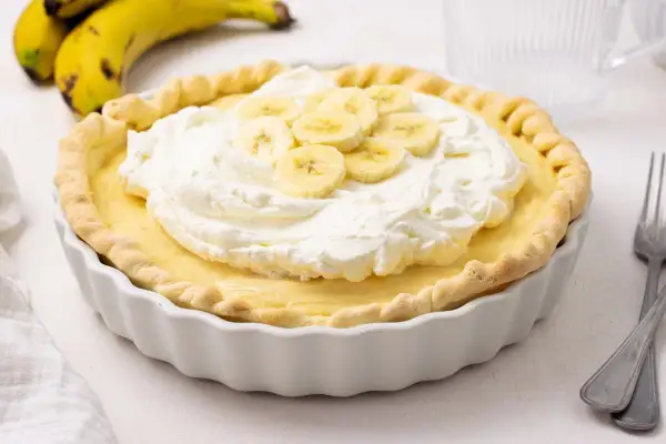 Deliciosa tarta de plátano con crema batida y rodajas de plátano fresco.