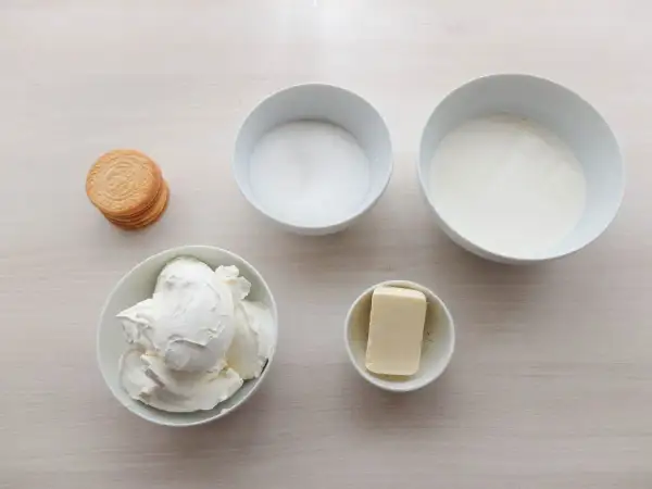 Ingredientes para tarta de queso sin horno: queso crema, azúcar, nata, mantequilla y galletas.