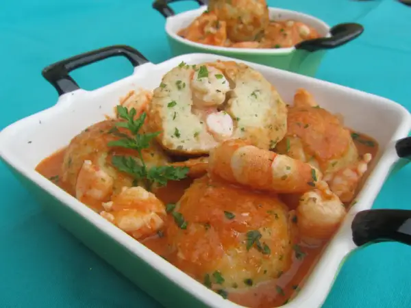 Albondigas de rape con gambas en salsa, servidas en cazuelas verdes y blancas, decoradas con perejil fresco.