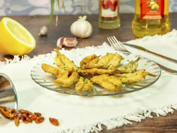 Un plato de boquerones en adobo crujientes, servidos con limón, ajo y guindillas.