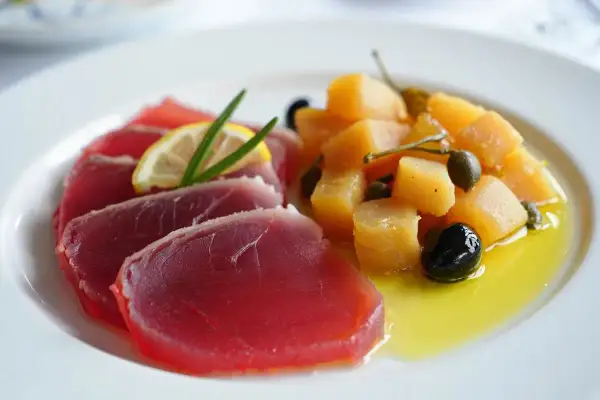 Deliciosa ventresca de atún cruda, servida con patatas, aceitunas y alcaparras en aceite de oliva.